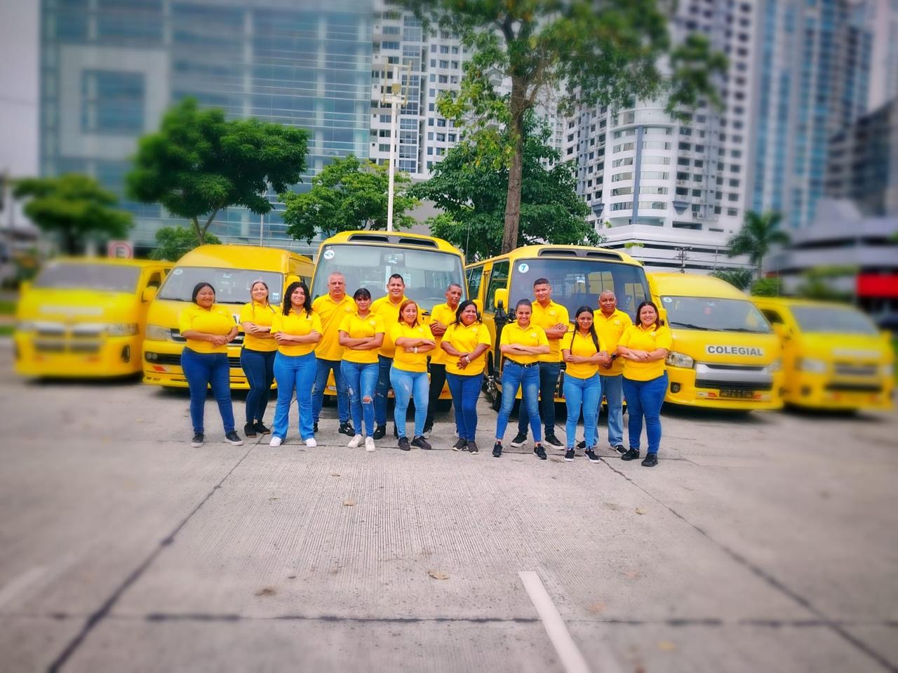 Equipo de trabajo de Tule Express con camisas amarillas frente a los buses de la flota